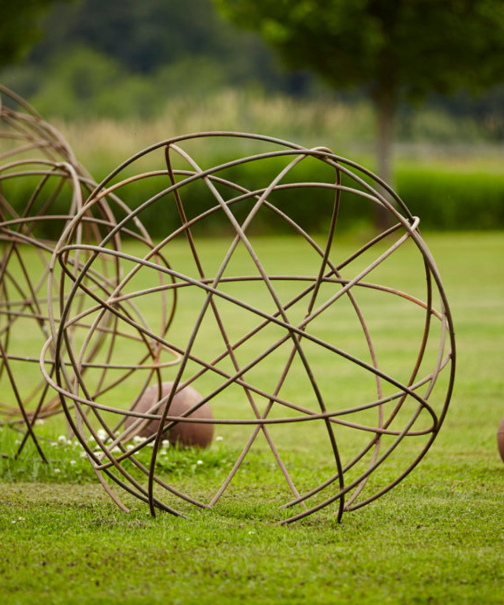 A dramatic landscape feature, the Jackson Metal Sphere, functions as an attractive garden outdoor sculpture and is very popular with interior and exterior designers. Available in grey charcoal steel or a rusted finish. Also shown in the photo are the Studio Sturdy large Lunar Steel Balls in rust.