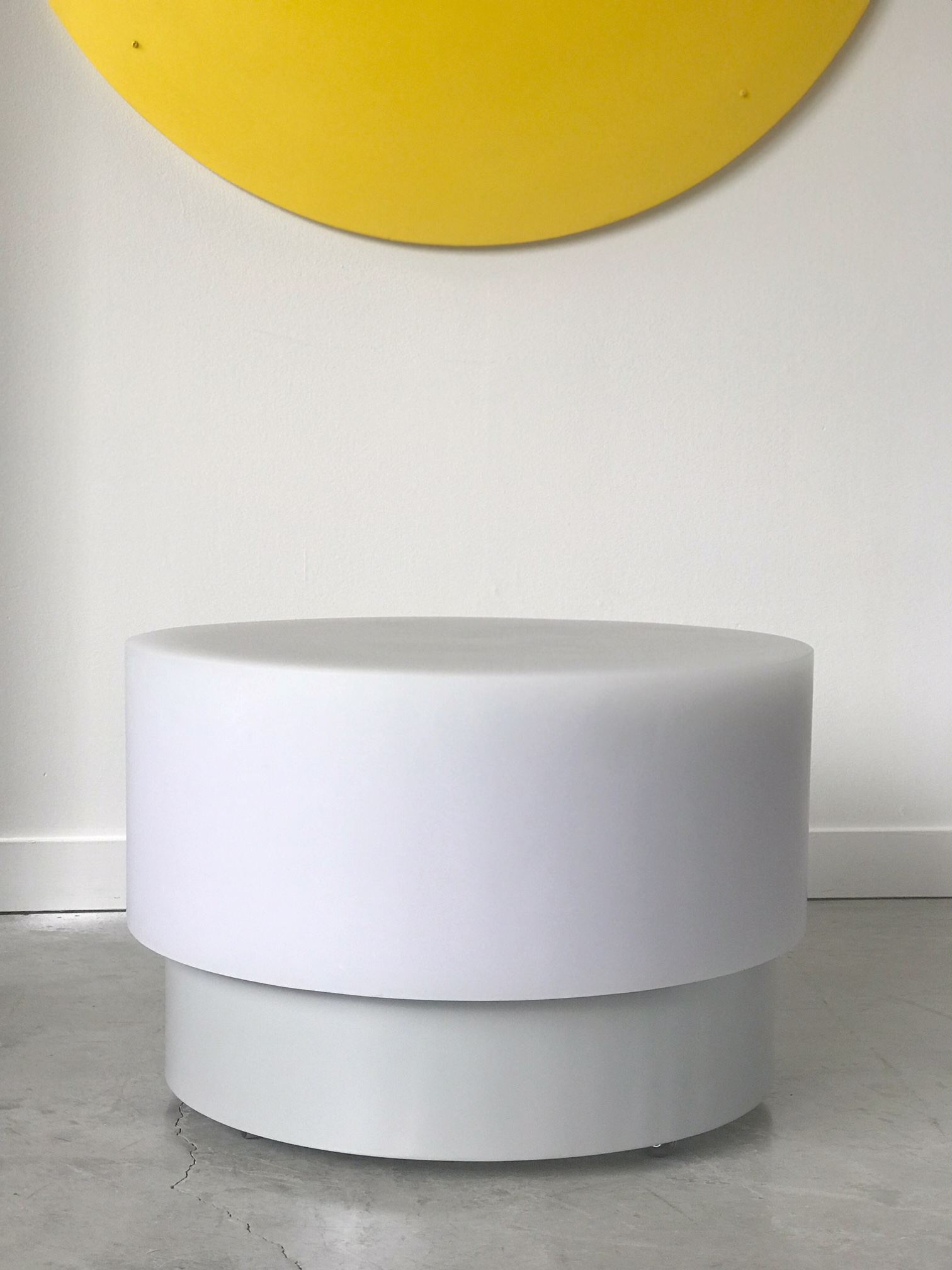 floating round resin coffee table with yellow wall accent