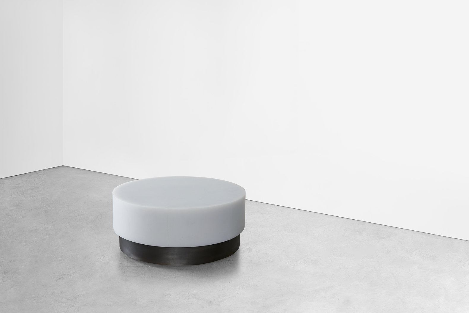 A contemporary round coffee table has a modern feel while maintaining a classic aesthetic and is shown in a homes interior with a white resin top and a steel base